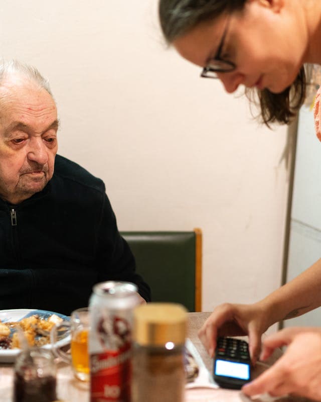 Hoitaja avustaa vanhusta aterialla